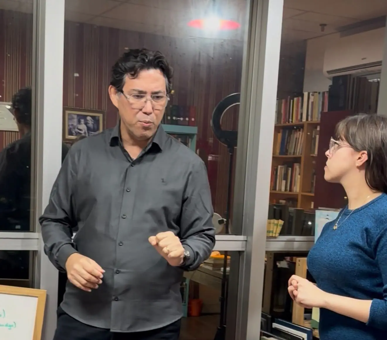 Fabio Blanco em pé, demonstrando um gesto com as mãos diante de uma aluna