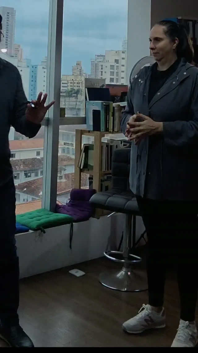 Aluna em pé aguardando a sua vez enquanto Fabio Blanco, à esquerda, gesticula durante a orientação